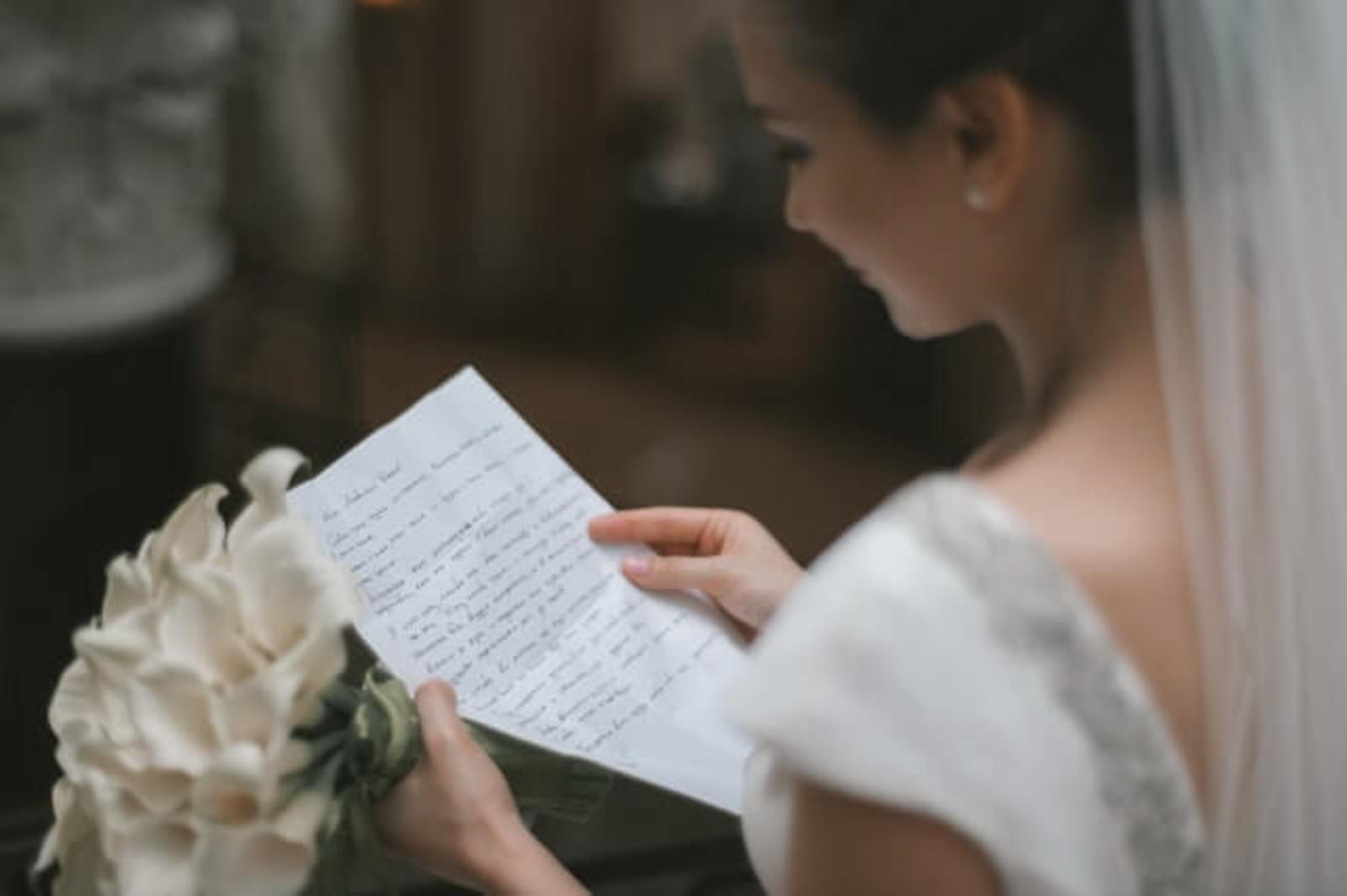 Kytica z ľalií v rukách nevesty čítajúcej list
